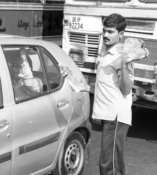 A man doing brisk business by selling bottled drinking water at traffic lights in Delhi